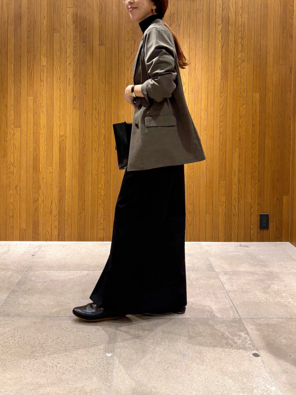 ブラック系のスカート、ブラック系のニット/セーター、ブラック系のハンドバッグを着用したレディースの秋コーディネートの3枚目の写真