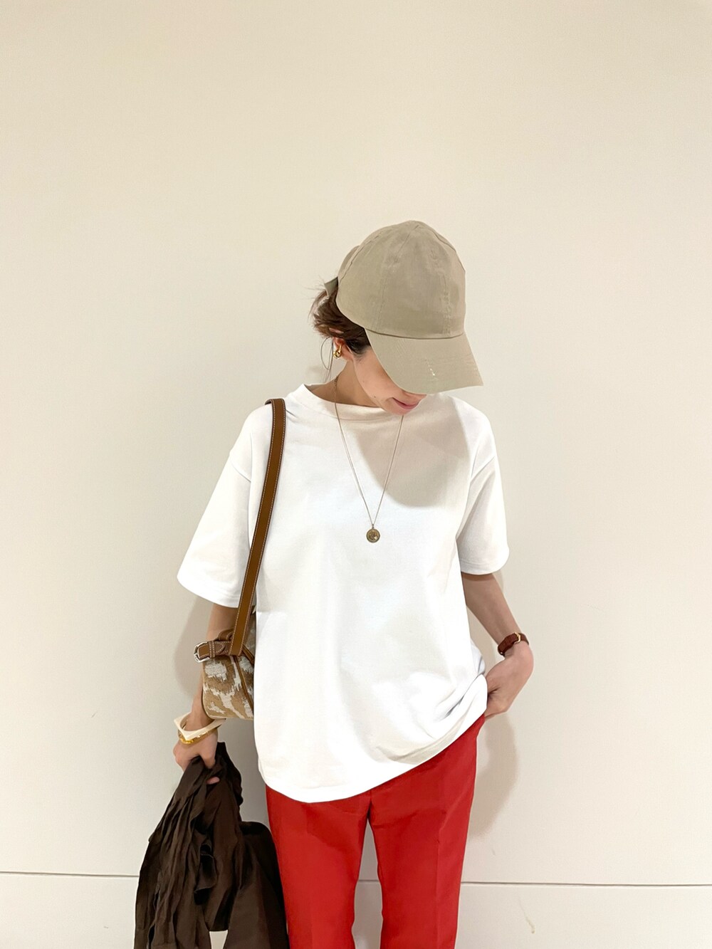 レッド系のその他パンツ、ホワイト系のTシャツ/カットソー、ブラウン系のバッグを着用したレディースの春コーディネートの3枚目の写真