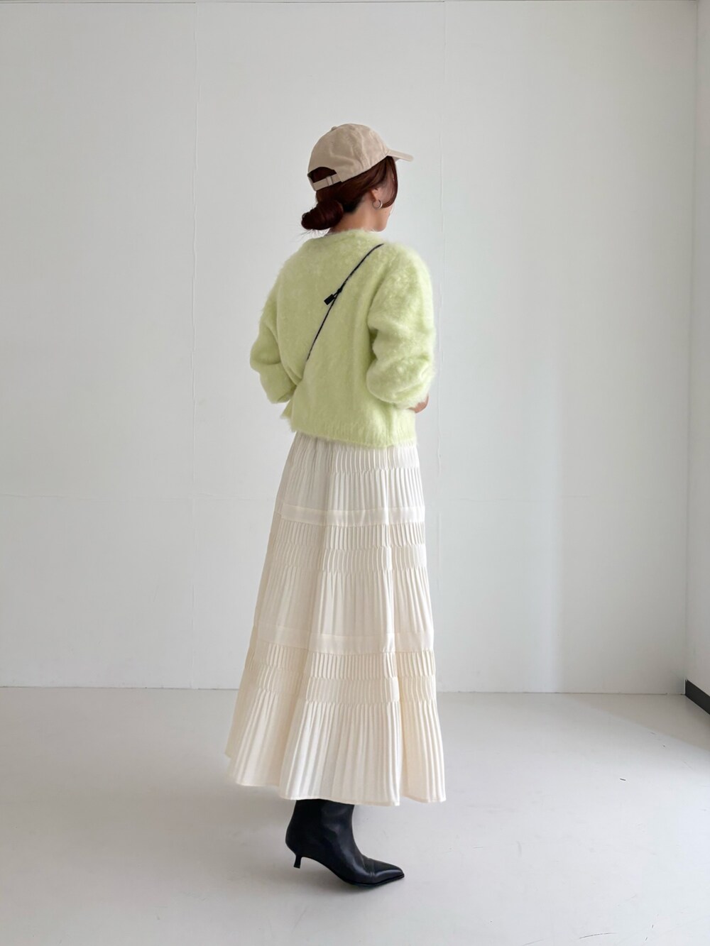 ホワイト系のスカート、グリーン系のカーディガン/ボレロ、ブラック系のブーツを着用したレディースの秋コーディネートの5枚目の写真