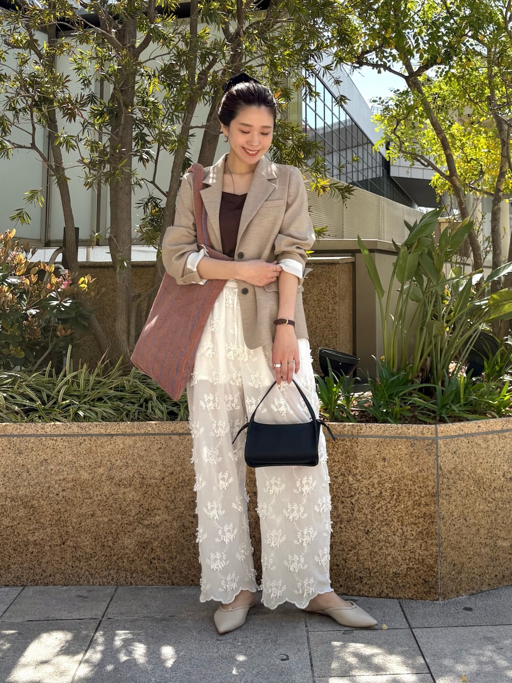 ベージュ系のその他アウター、ホワイト系のその他パンツ、ブラック系のハンドバッグを着用したレディースの春コーディネートの4枚目の写真