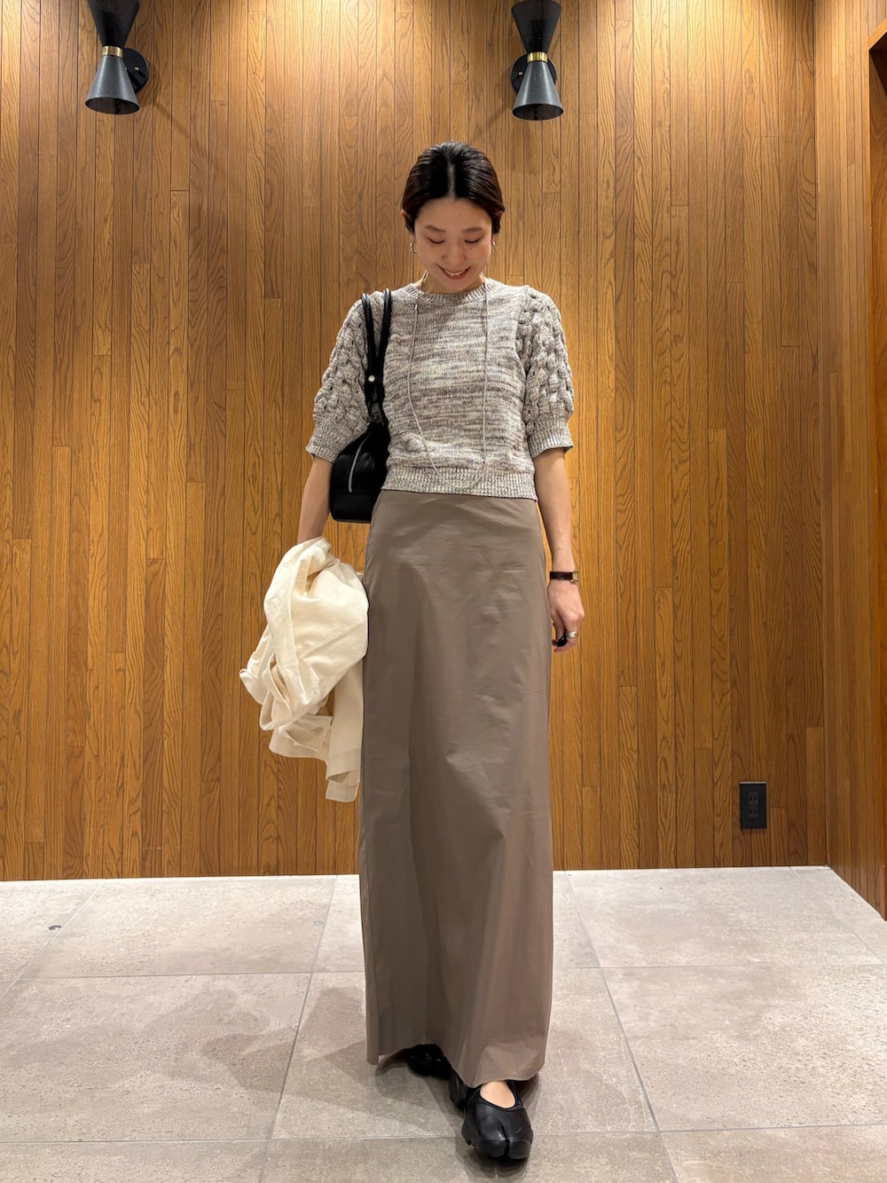 グレー系のスカート、その他のニット/セーター、ブラック系のスニーカーを着用したレディースの春コーディネートの6枚目の写真