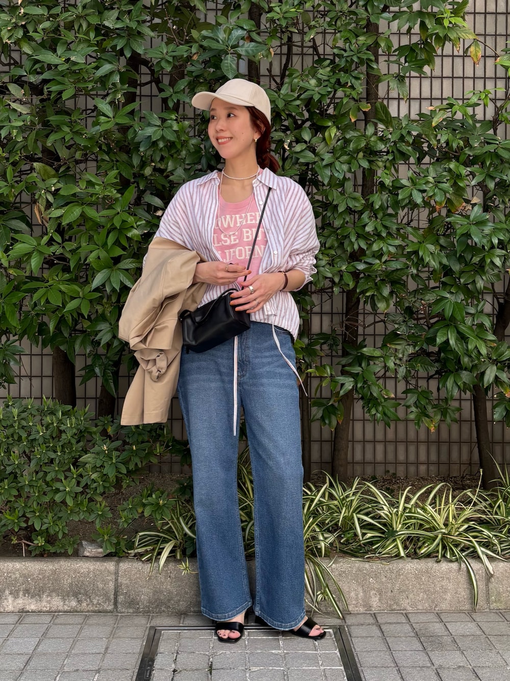 レッド系のシャツ/ブラウス、ベージュ系のトレンチコート、ブルー系のデニムパンツを着用したレディースの春コーディネートの5枚目の写真