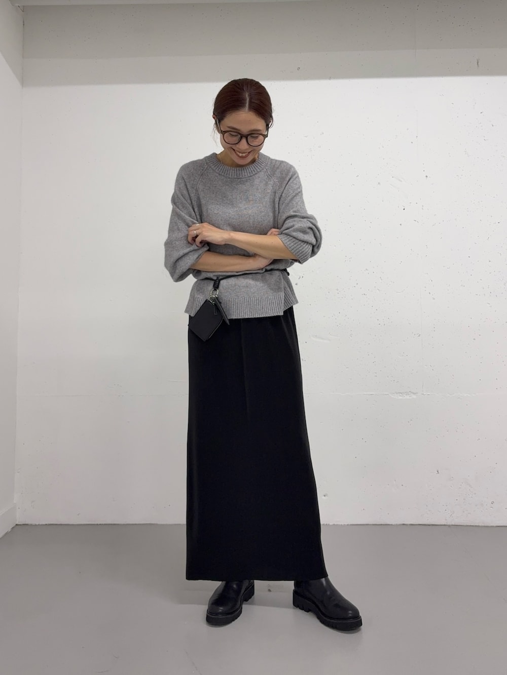 グレー系のニット/セーター、ブラック系のショルダーバッグ、ブラック系のスカートを着用したレディースの秋コーディネートの5枚目の写真