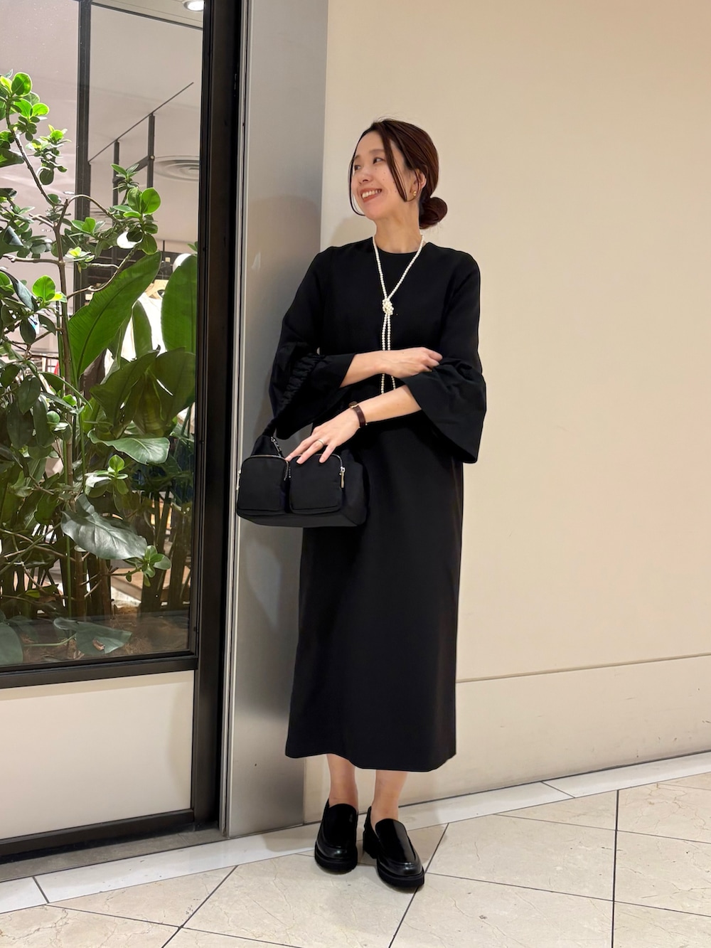 ブラック系のワンピース、ブラック系のローファー、ブラック系のショルダーバッグを着用したレディースの冬コーディネートの5枚目の写真