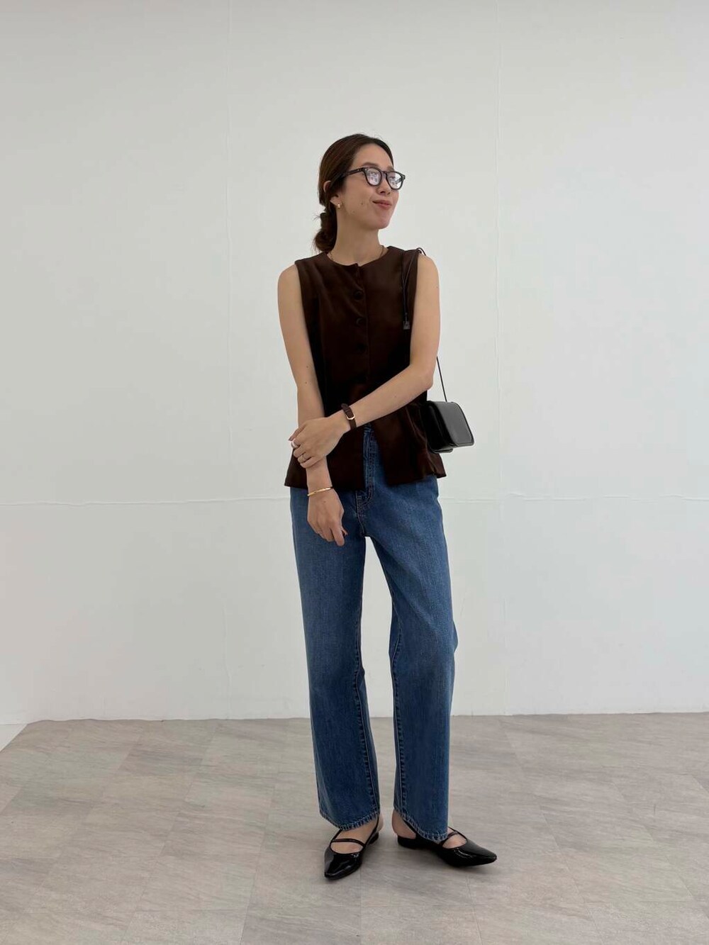 ブラック系のショルダーバッグ、ブラック系のパンプス、ブルー系のデニムパンツを着用したレディースの夏コーディネートの5枚目の写真