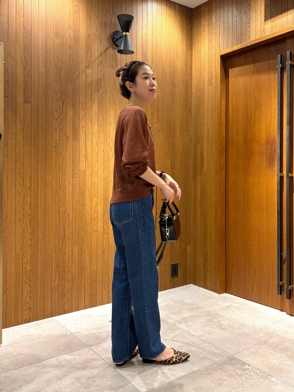 ブルー系のデニムパンツ、ブラック系のショルダーバッグ、ブラウン系のカーディガン/ボレロを着用したレディースの秋コーディネートの3枚目の写真