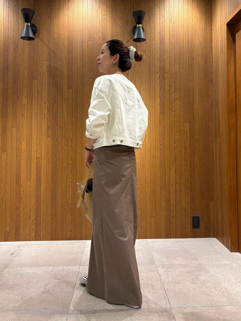 グレー系のスカート、ホワイト系のTシャツ/カットソー、ベージュ系のハンドバッグを着用したレディースの春コーディネートの4枚目の写真