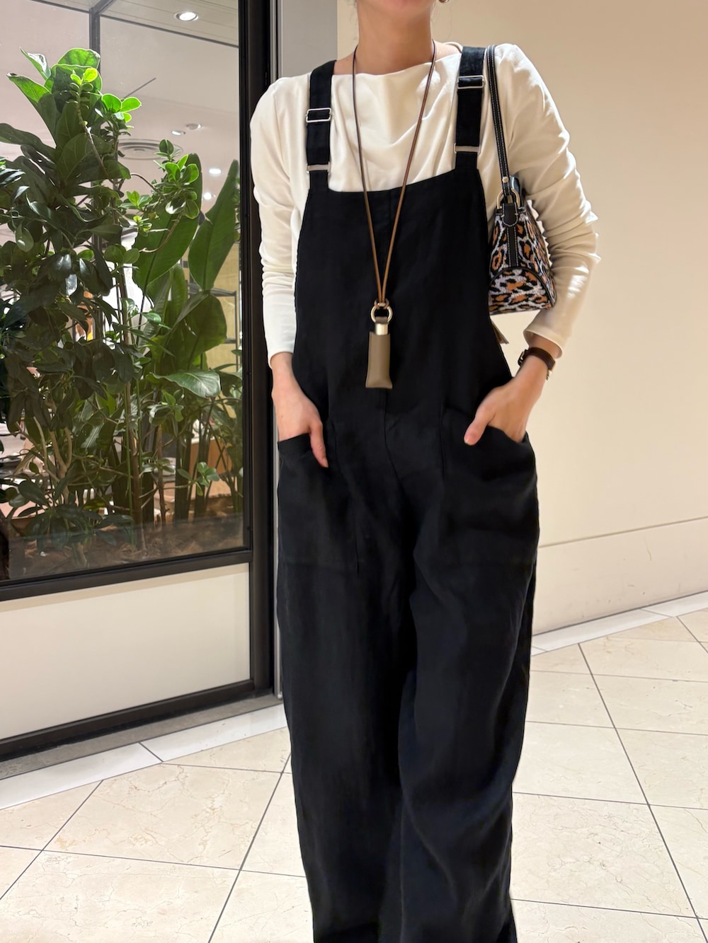 ブラック系のサロペット/オーバーオール、ホワイト系のTシャツ/カットソー、パープル系のハンドバッグを着用したレディースの春コーディネートの5枚目の写真