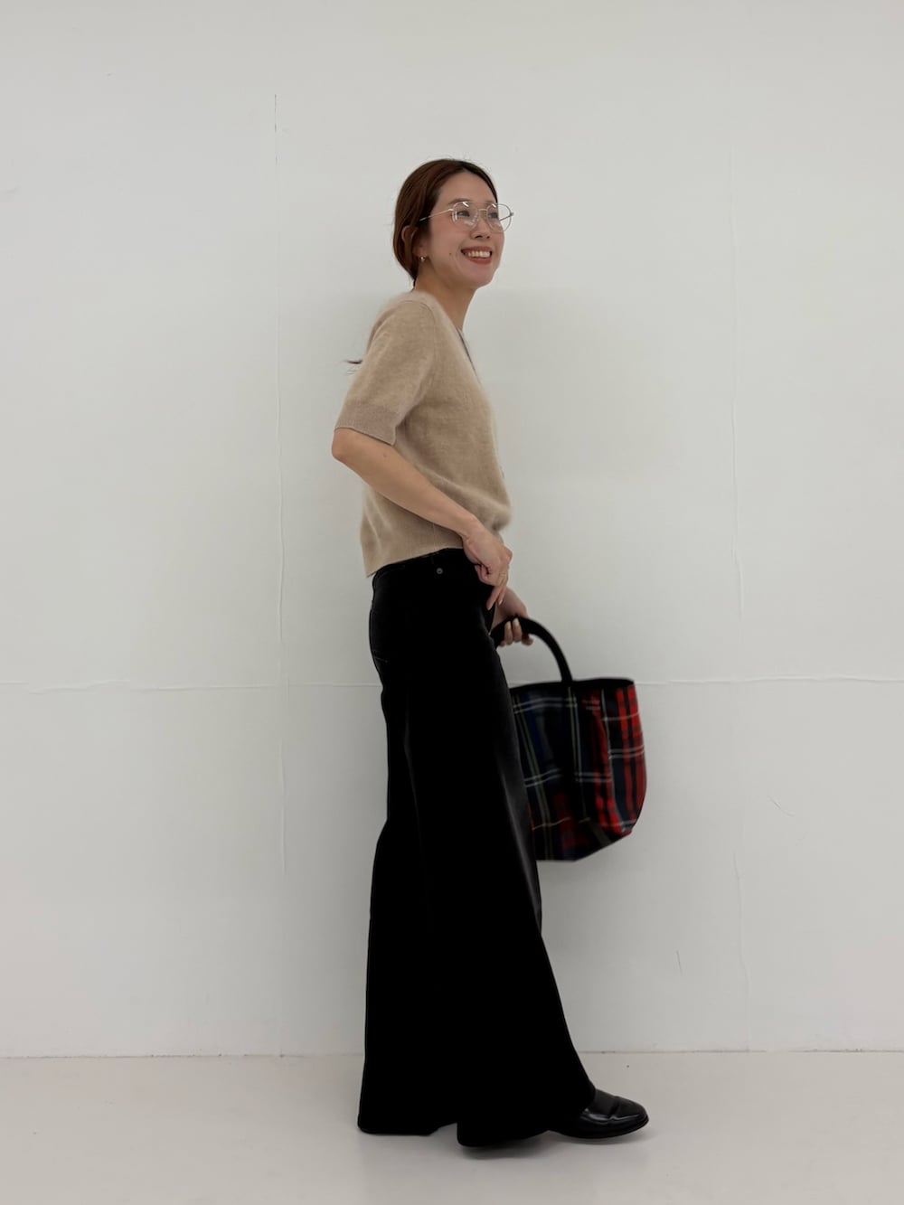 ブラック系のデニムパンツ、グレー系のトートバッグ、ベージュ系のニット/セーターを着用したレディースの夏コーディネートの2枚目の写真