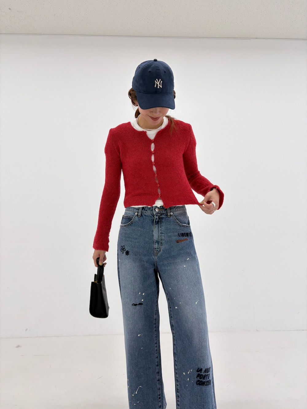 ブルー系のデニムパンツ、ホワイト系のTシャツ/カットソー、ブラック系のハンドバッグを着用したレディースの夏コーディネートの7枚目の写真
