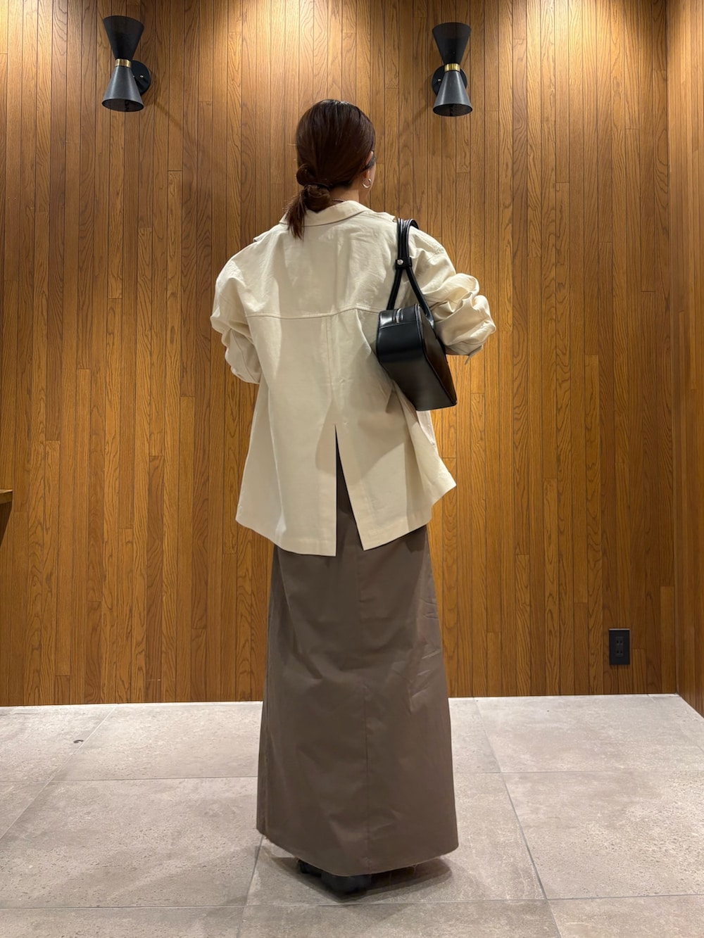 グレー系のスカート、その他のニット/セーター、ブラック系のスニーカーを着用したレディースの春コーディネートの3枚目の写真