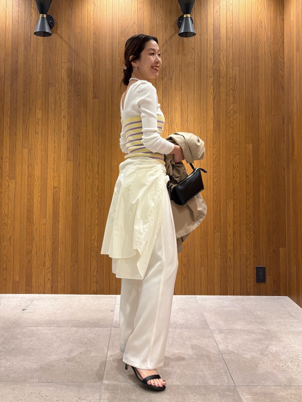 ベージュ系のトレンチコート、イエロー系のニット/セーター、ホワイト系のその他パンツを着用したレディースの春コーディネートの6枚目の写真
