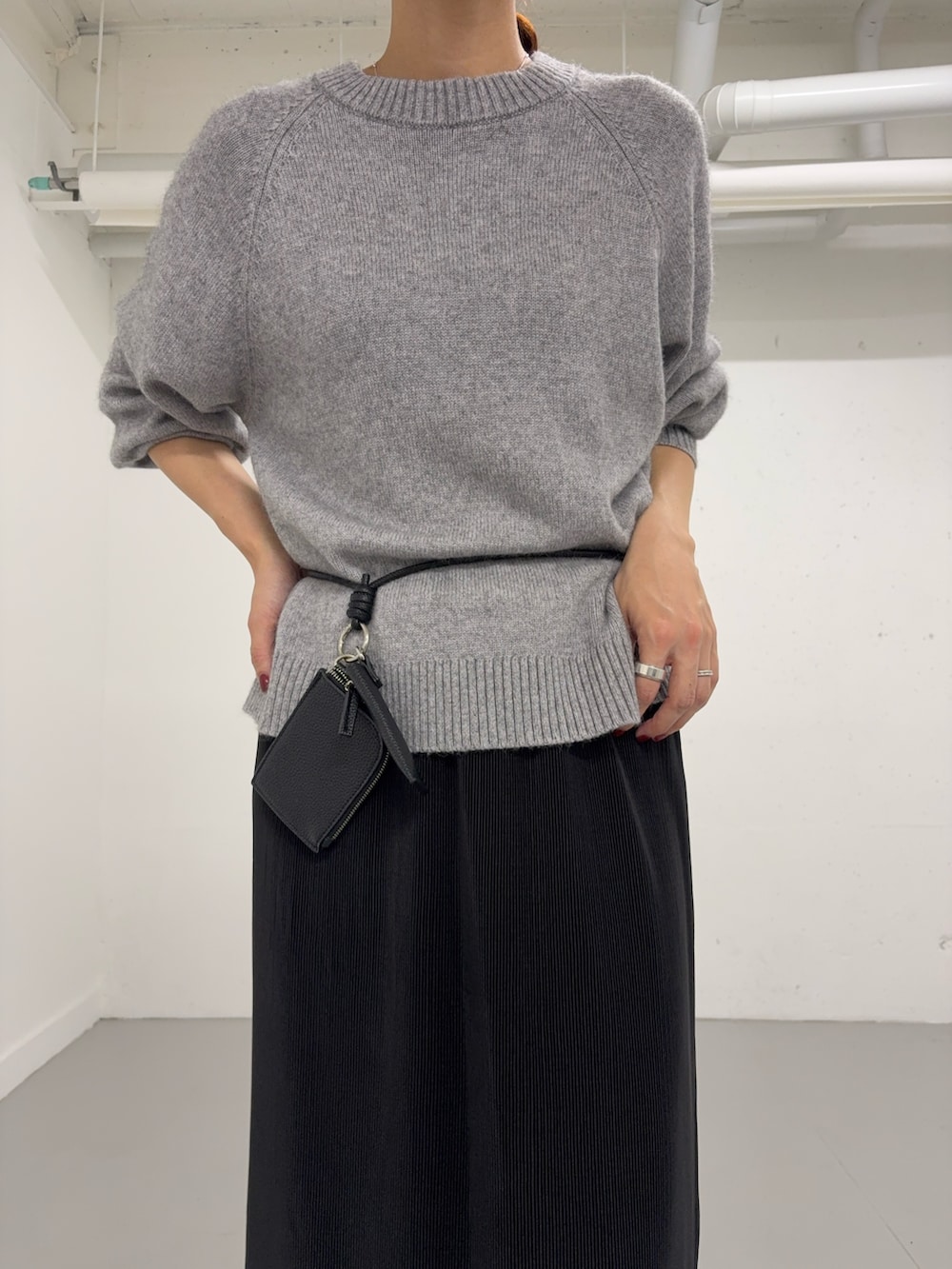 グレー系のニット/セーター、ブラック系のショルダーバッグ、ブラック系のスカートを着用したレディースの秋コーディネートの6枚目の写真