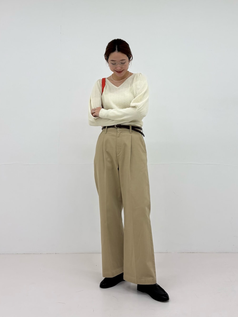 ホワイト系のニット/セーター、ベージュ系のその他パンツ、ブラック系のローファーを着用したレディースの夏コーディネートの6枚目の写真
