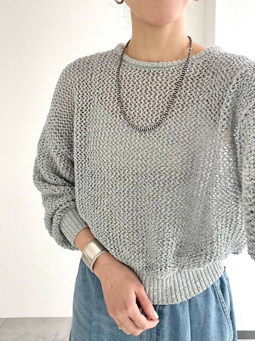 ベージュ系のボストンバッグ、グレー系のニット/セーター、ホワイト系のスニーカーを着用したレディースの春コーディネートの5枚目の写真