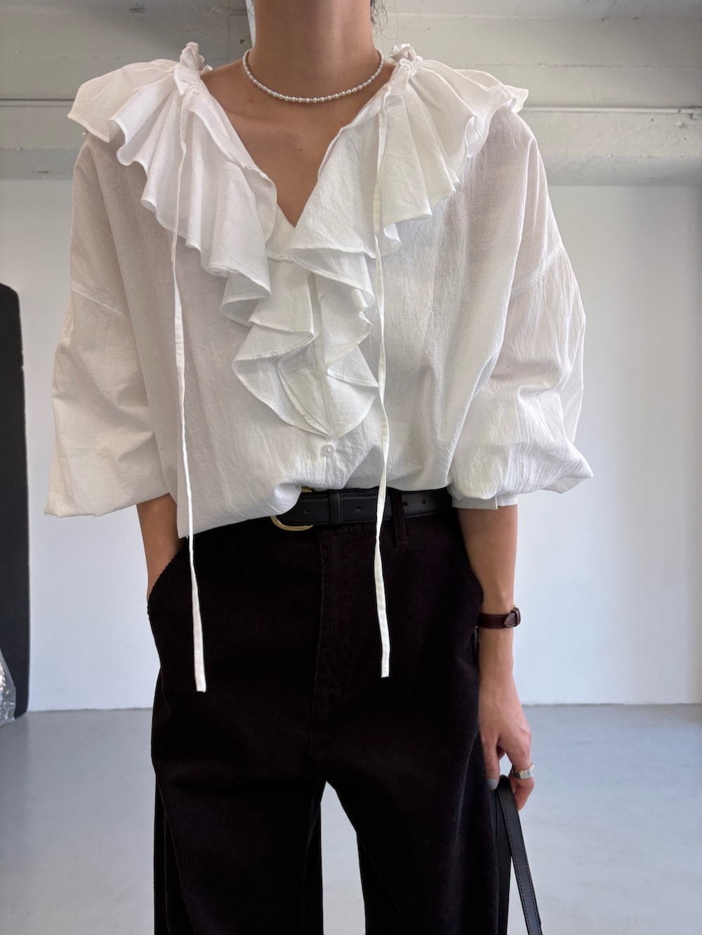 グレー系のその他パンツ、ホワイト系のシャツ/ブラウス、ブラック系のハンドバッグを着用したレディースの秋コーディネートの7枚目の写真