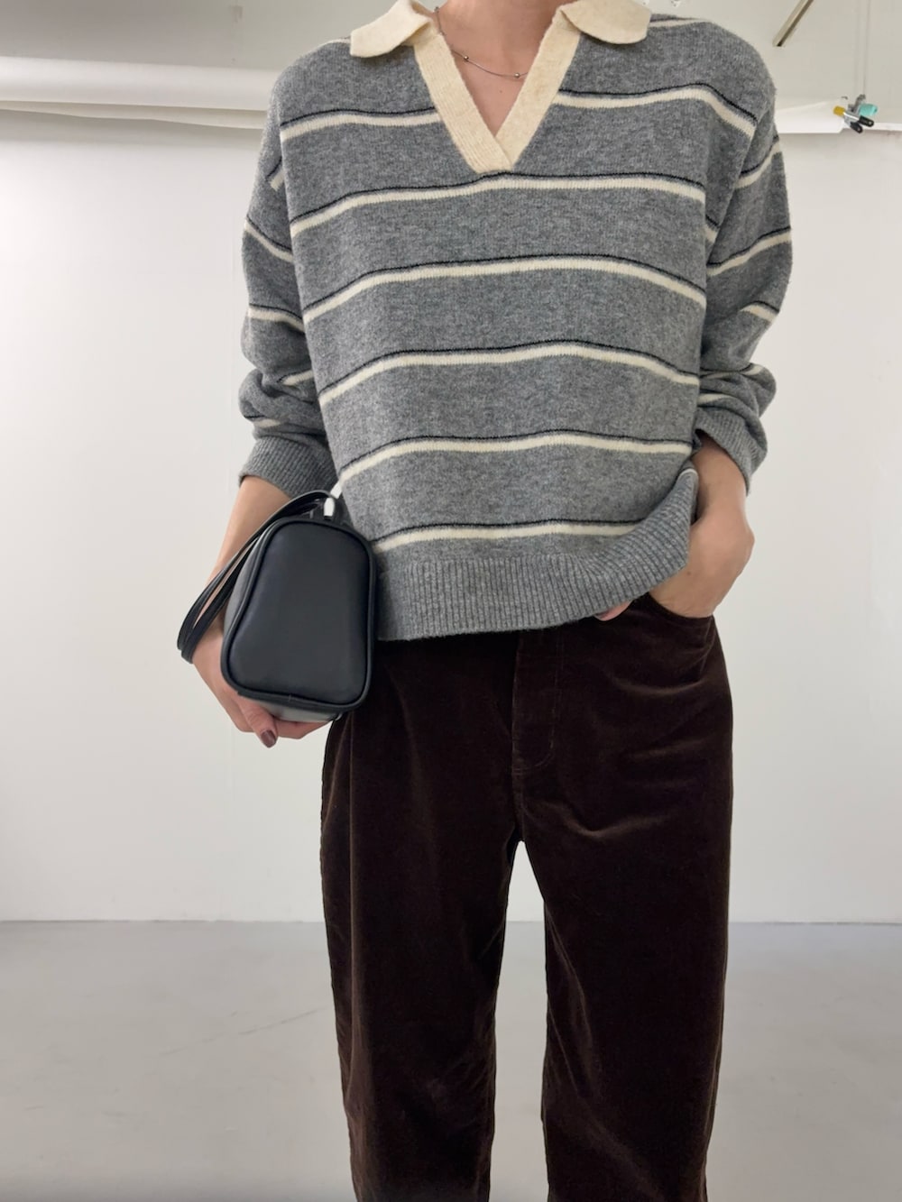 グレー系のニット/セーター、ブラウン系のその他パンツ、ブラック系のハンドバッグを着用したレディースの秋コーディネートの6枚目の写真