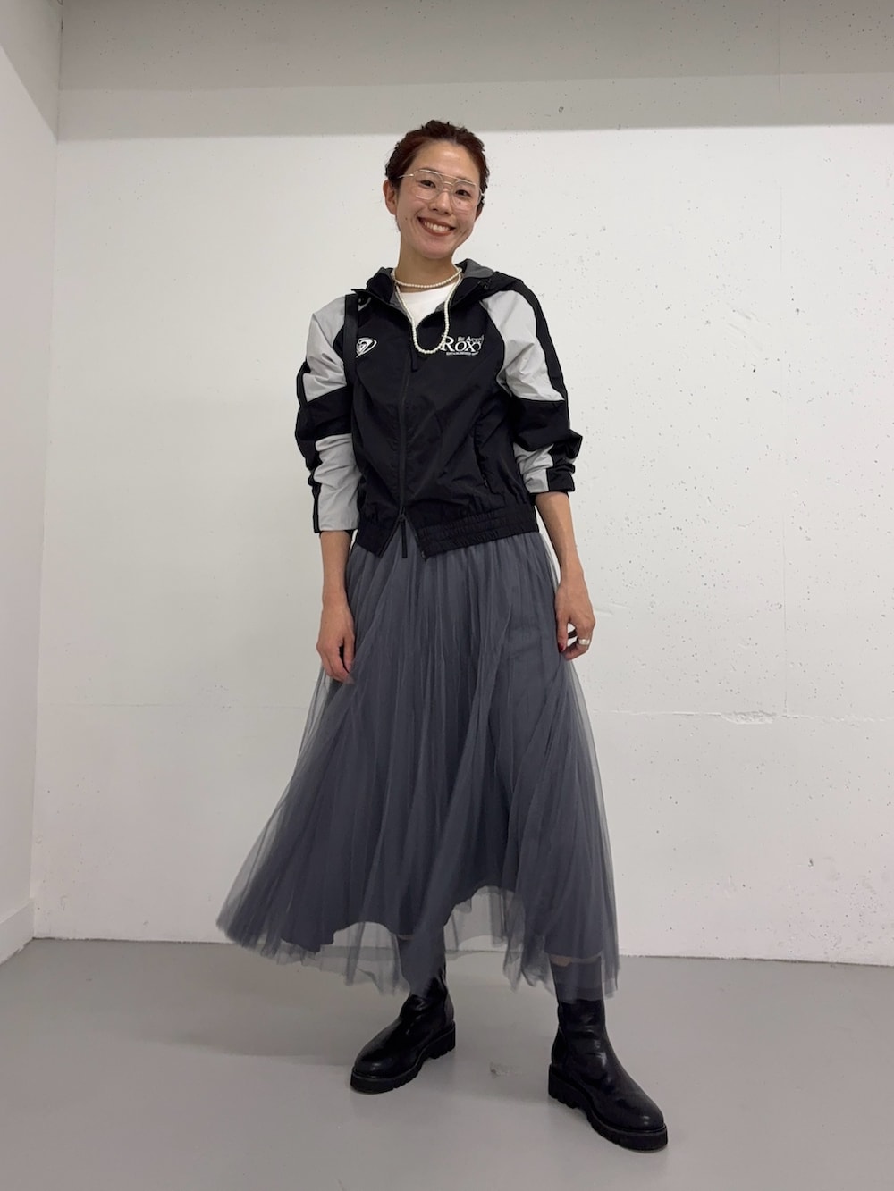 グレー系のスカート、ブラック系のナイロンジャケット、ブラック系のブーツを着用したレディースの夏コーディネートの5枚目の写真