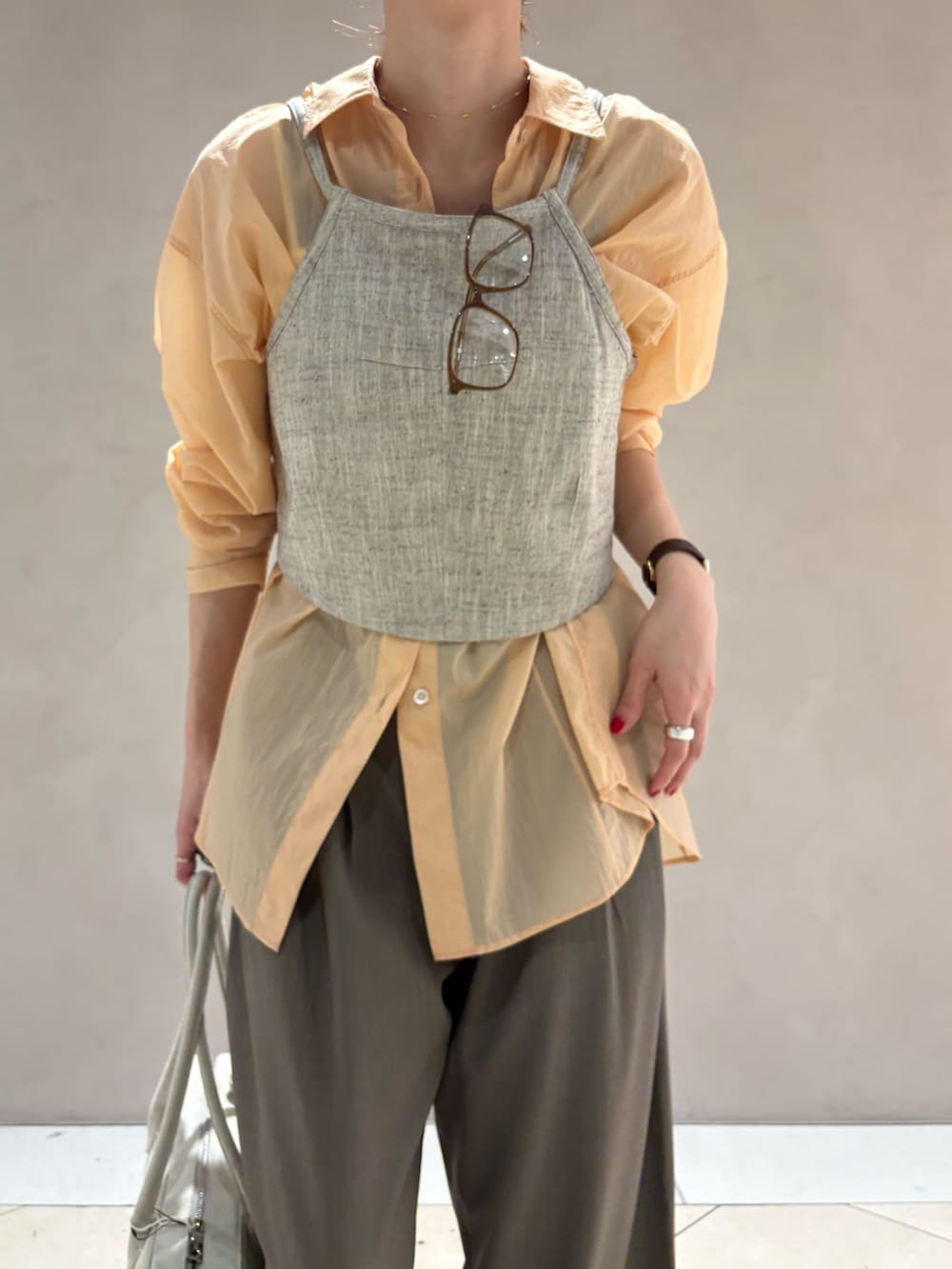 オレンジ系のシャツ/ブラウス、ベージュ系のその他トップス、ホワイト系のスニーカーを着用したレディースの春コーディネートの5枚目の写真