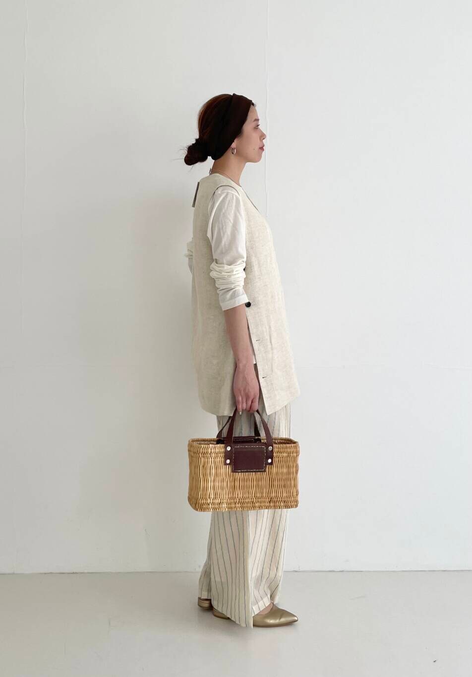 ベージュ系のベスト、ブラウン系のかごバッグ、ベージュ系のその他パンツを着用したレディースの春コーディネートの2枚目の写真