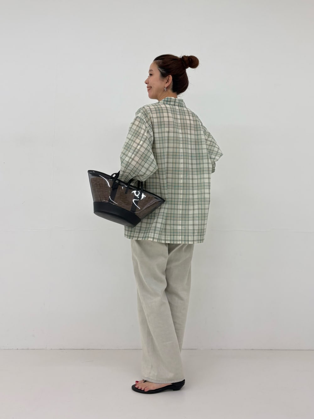 ブラック系のかごバッグ、グレー系のデニムパンツ、ブラック系のサンダルを着用したレディースの春コーディネートの3枚目の写真