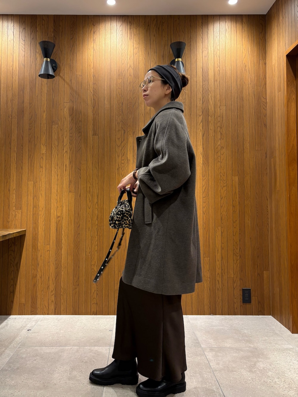 グリーン系のステンカラーコート、ブラウン系のスカート、その他のハンドバッグを着用したレディースの冬コーディネートの3枚目の写真