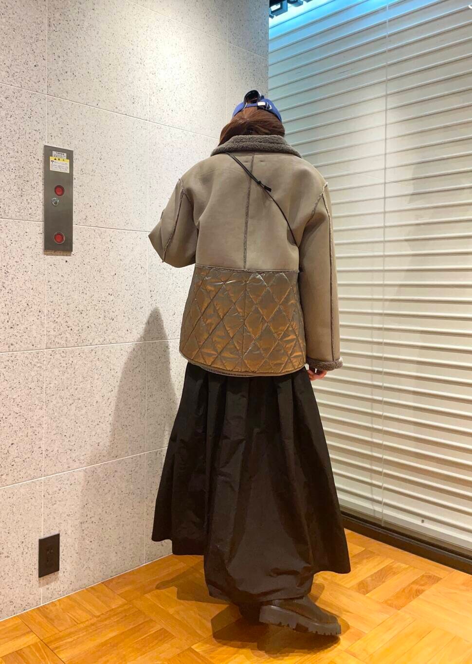 グレー系のその他アウター、ブラック系のブーツ、ブラック系のスカートを着用したレディースの冬コーディネートの4枚目の写真