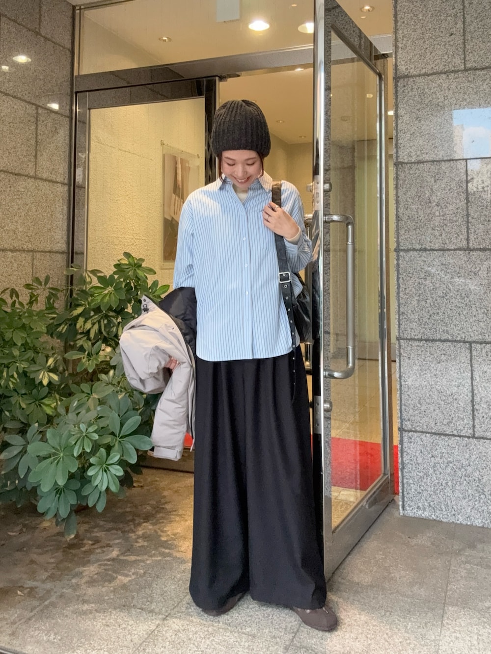 グレー系のダウンジャケット/コート、ブラック系のその他パンツ、ブラウン系のスニーカーを着用したレディースの秋コーディネートの6枚目の写真