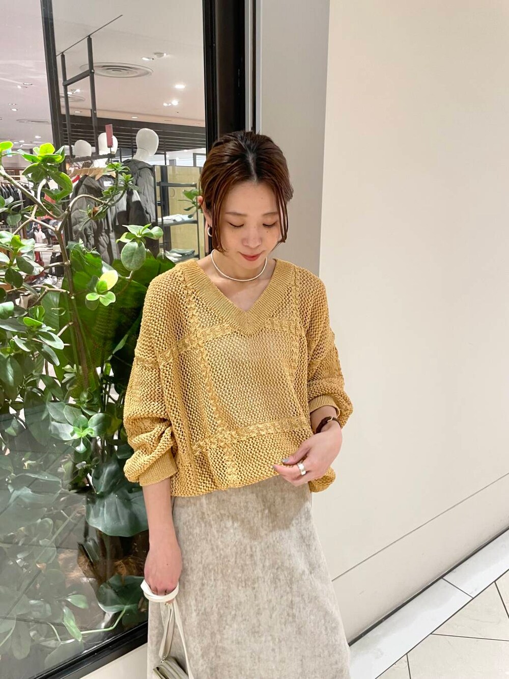 ホワイト系のショルダーバッグ、ベージュ系のスカート、イエロー系のニット/セーターを着用したレディースの冬コーディネートの5枚目の写真