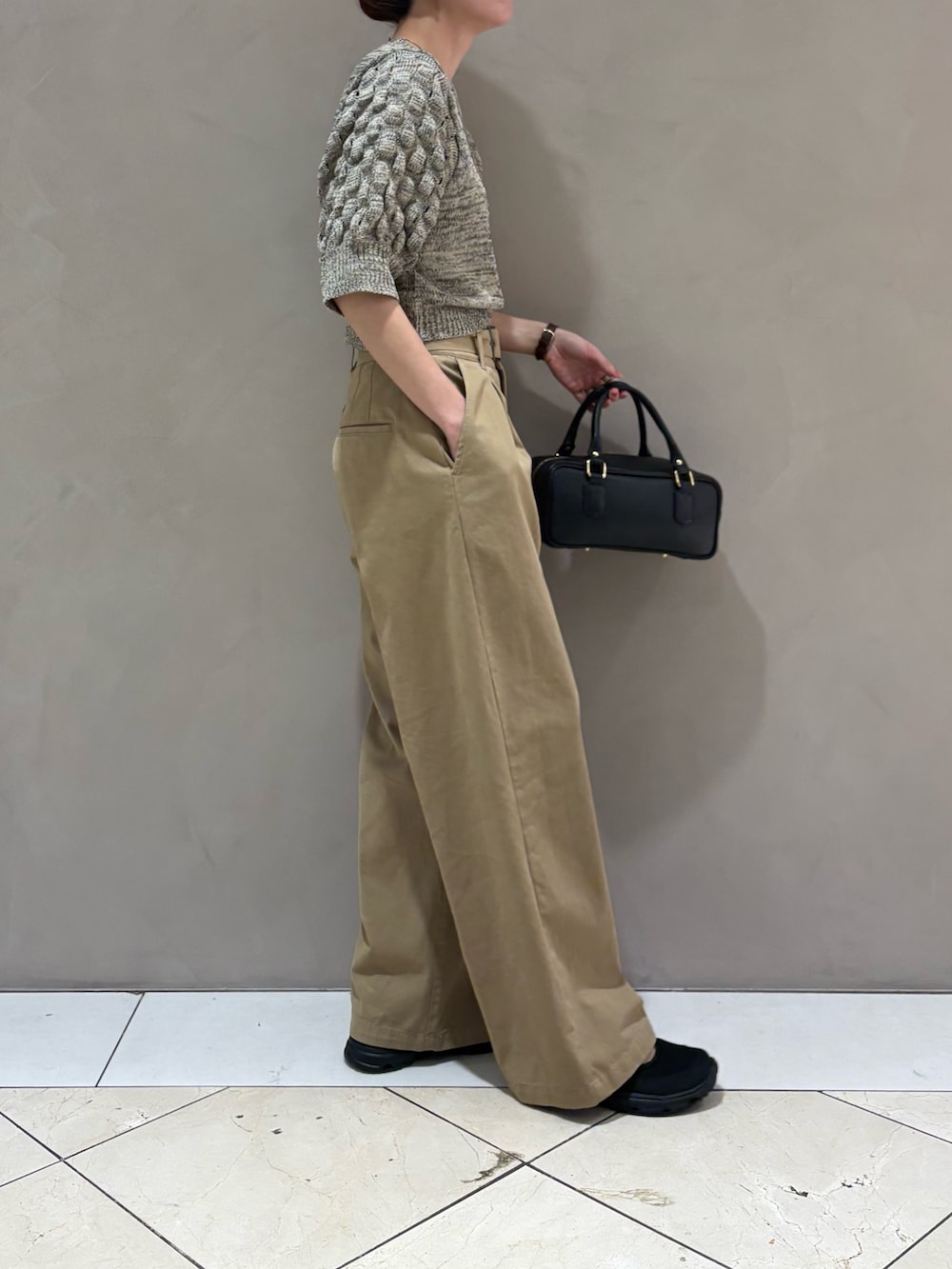 ベージュ系のその他パンツ、ブラック系のハンドバッグ、ホワイト系のニット/セーターを着用したレディースの春コーディネートの2枚目の写真