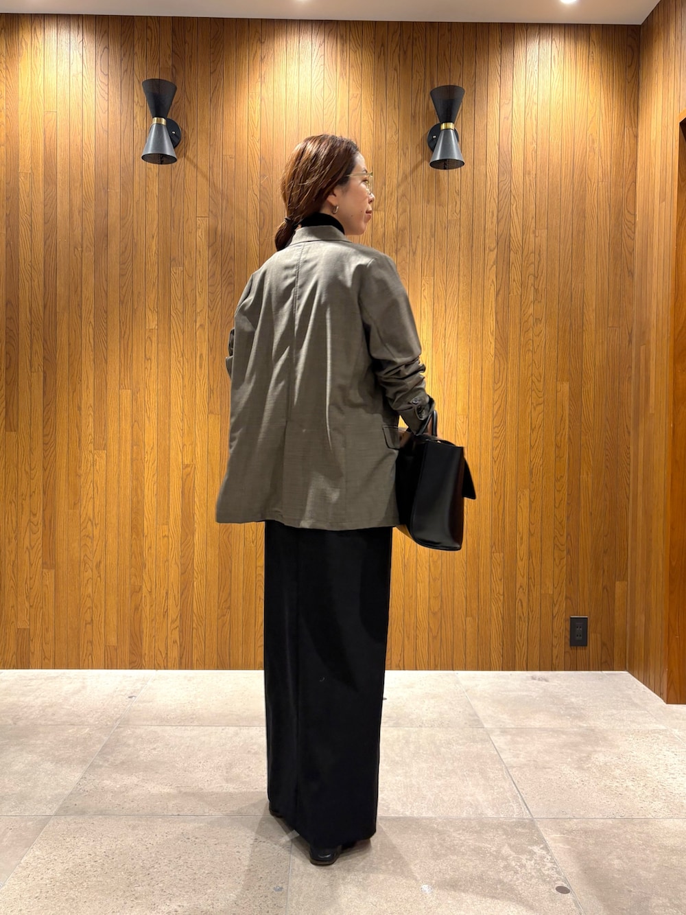 ブラック系のスカート、ブラック系のニット/セーター、ブラック系のハンドバッグを着用したレディースの秋コーディネートの5枚目の写真