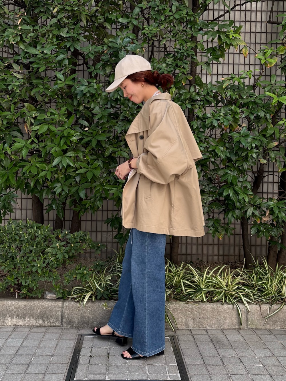 レッド系のシャツ/ブラウス、ベージュ系のトレンチコート、ブルー系のデニムパンツを着用したレディースの春コーディネートの2枚目の写真