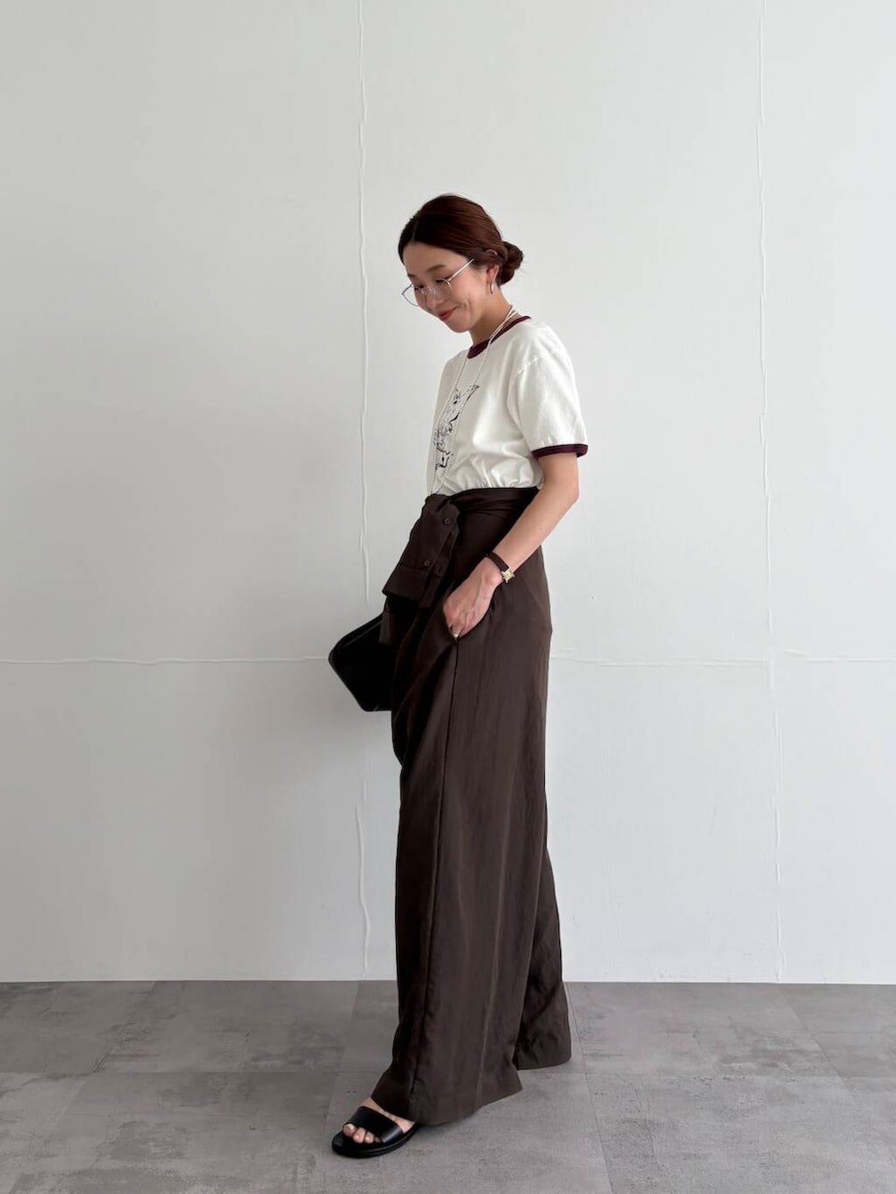 ブラウン系のサロペット/オーバーオール、ホワイト系のTシャツ/カットソー、ブラック系のサンダルを着用したレディースの春コーディネートの3枚目の写真