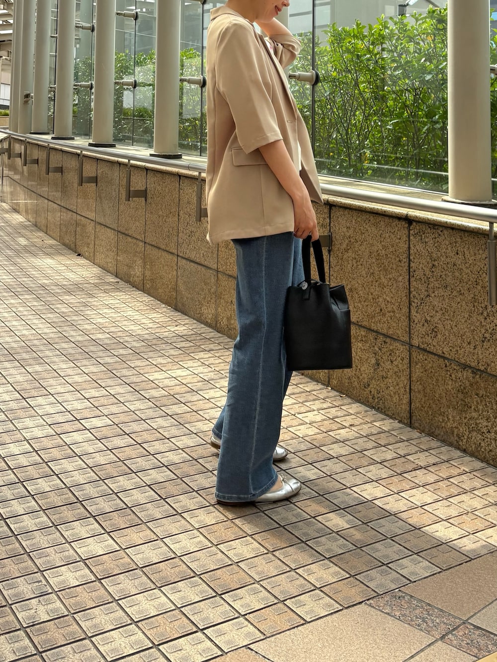 ブルー系のデニムパンツ、ベージュ系のその他アウター、ブラック系のハンドバッグを着用したレディースの春コーディネートの2枚目の写真