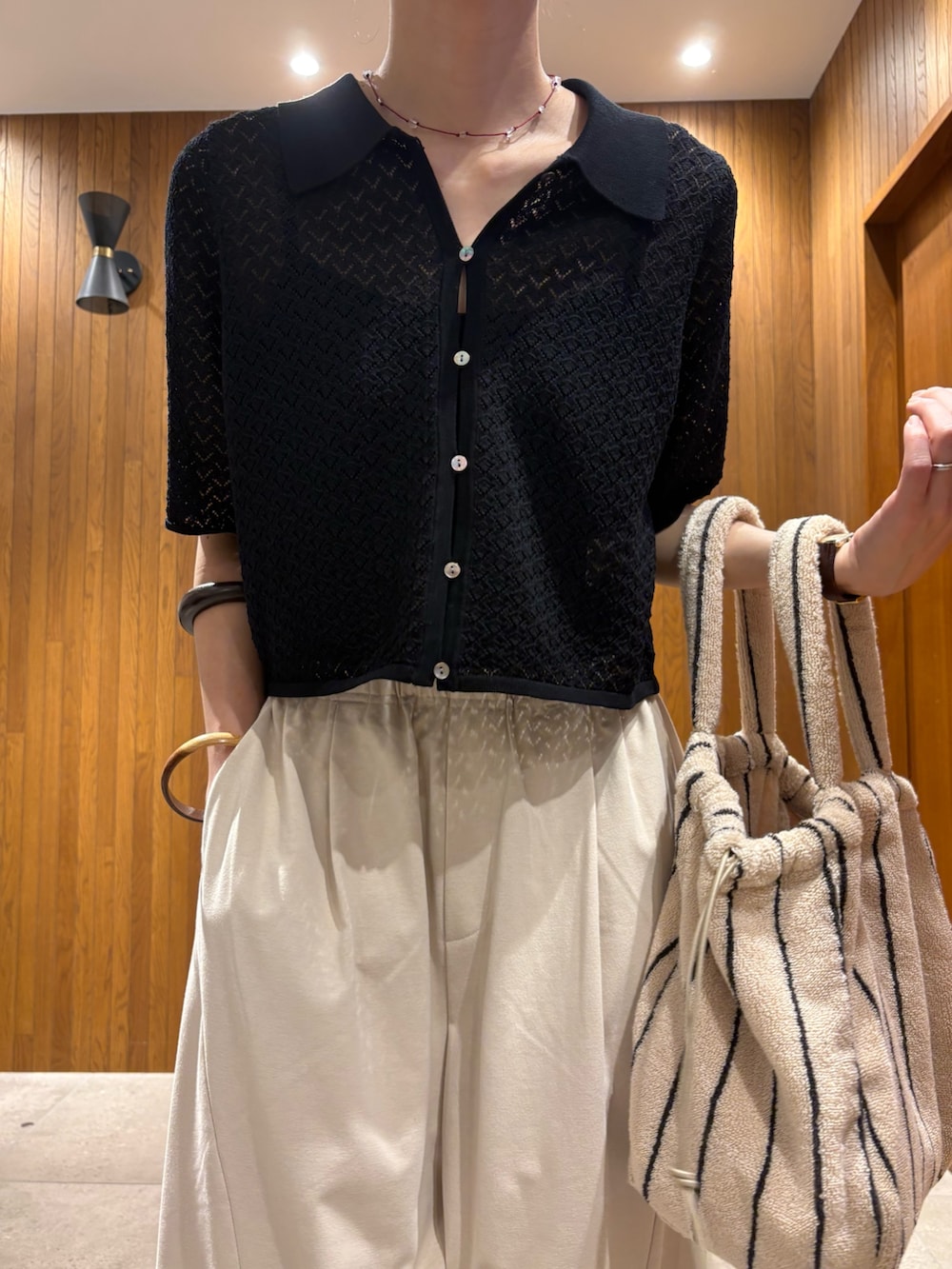 ブラック系のニット/セーター、ホワイト系のその他パンツ、ホワイト系のハンドバッグを着用したレディースの春コーディネートの5枚目の写真