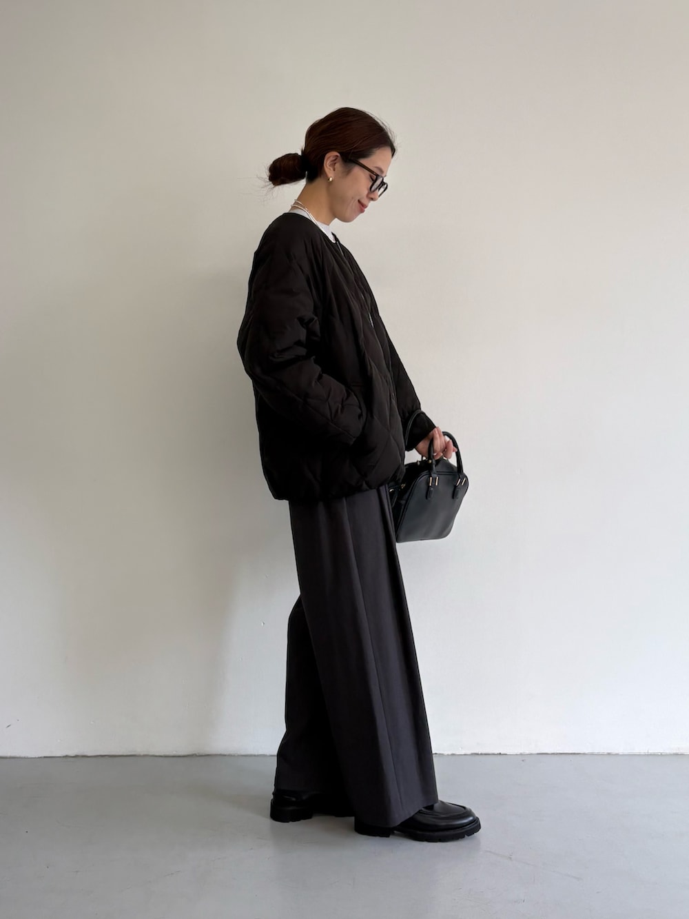 ブラック系のダウンジャケット/コート、グレー系のその他パンツ、ブラック系のローファーを着用したレディースの冬コーディネートの4枚目の写真