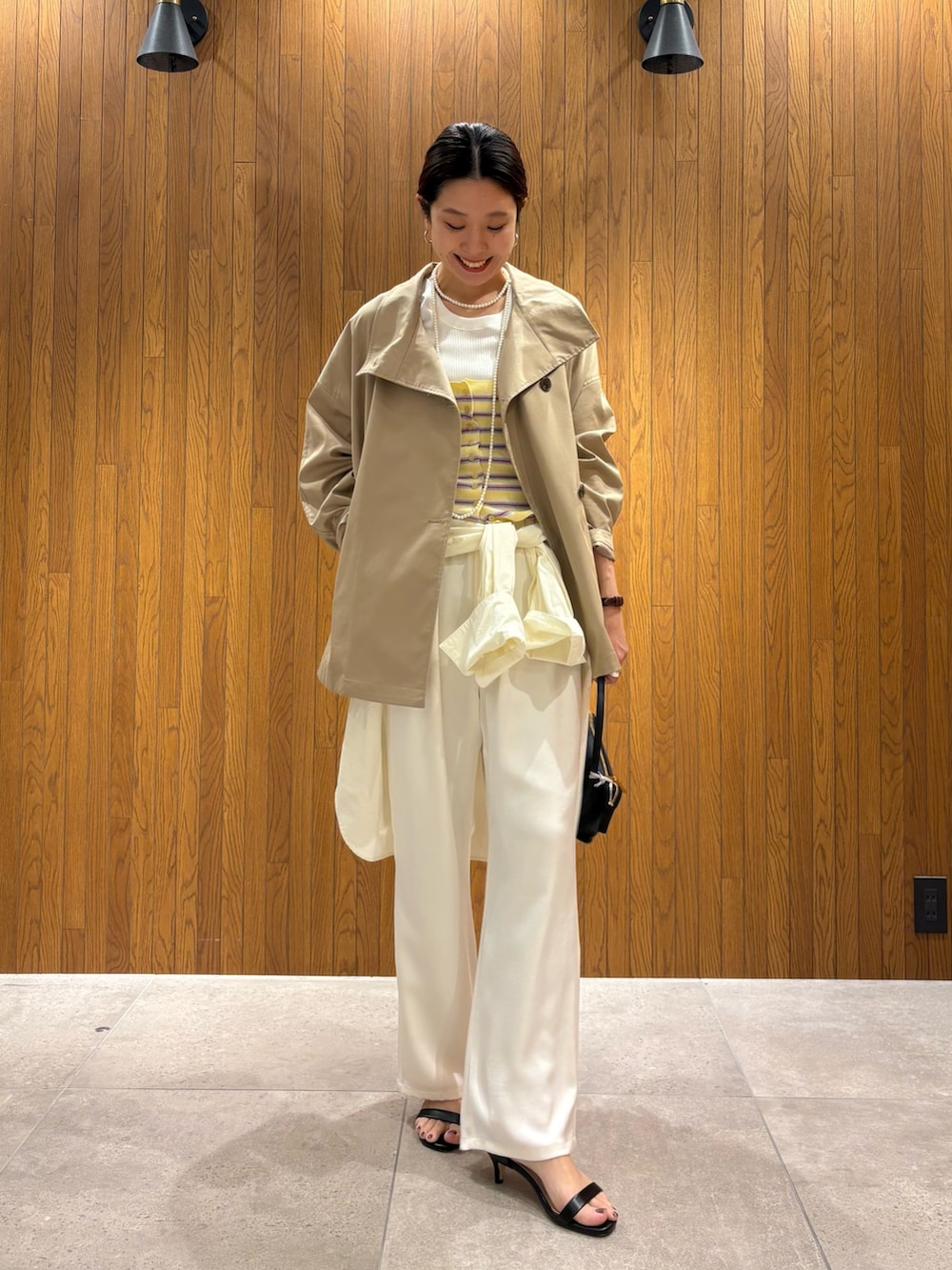 ベージュ系のトレンチコート、イエロー系のニット/セーター、ホワイト系のその他パンツを着用したレディースの春コーディネートの5枚目の写真