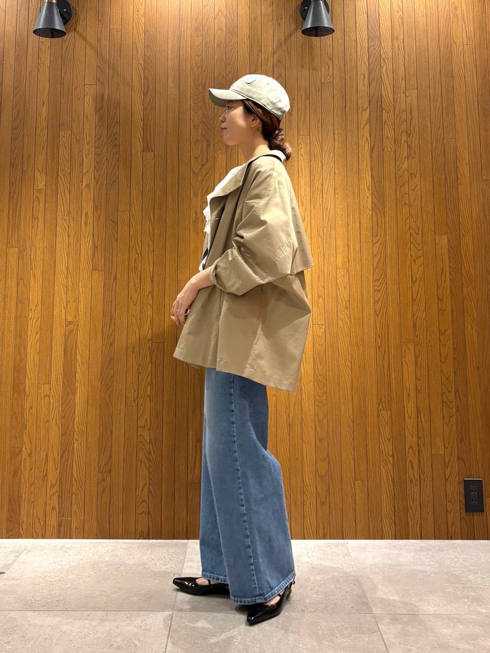 ベージュ系のトレンチコート、ホワイト系のシャツ/ブラウス、ブルー系のデニムパンツを着用したレディースの春コーディネートの2枚目の写真