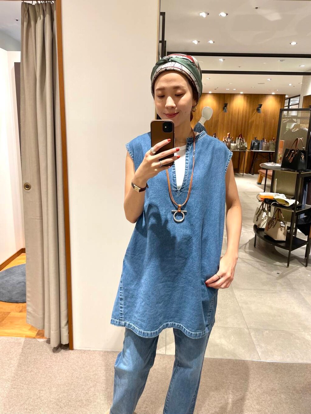 ホワイト系のタンクトップ、ブルー系のベスト、ブルー系のデニムパンツを着用したレディースの夏コーディネートの3枚目の写真