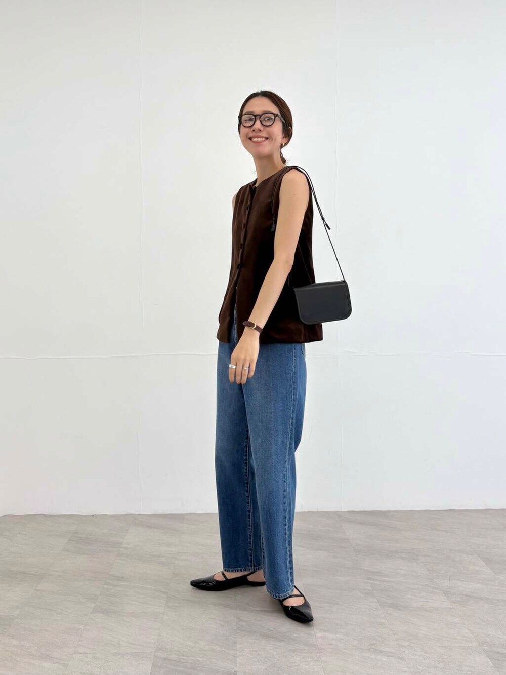 ブラック系のショルダーバッグ、ブラック系のパンプス、ブルー系のデニムパンツを着用したレディースの夏コーディネートの6枚目の写真