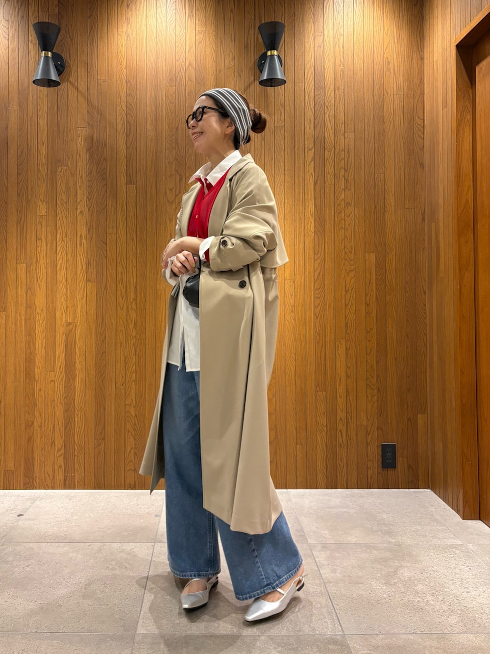 ベージュ系のトレンチコート、ブルー系のデニムパンツ、シルバー系のパンプスを着用したレディースの春コーディネートの2枚目の写真