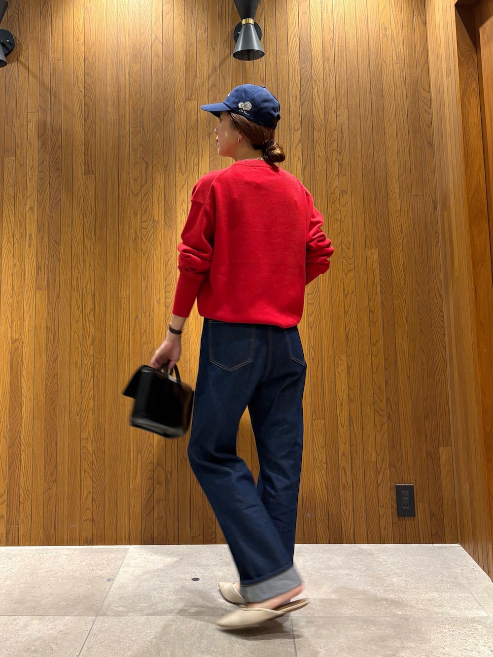 ブルー系のデニムパンツ、レッド系のニット/セーター、ブラック系のハンドバッグを着用したレディースの秋コーディネートの3枚目の写真