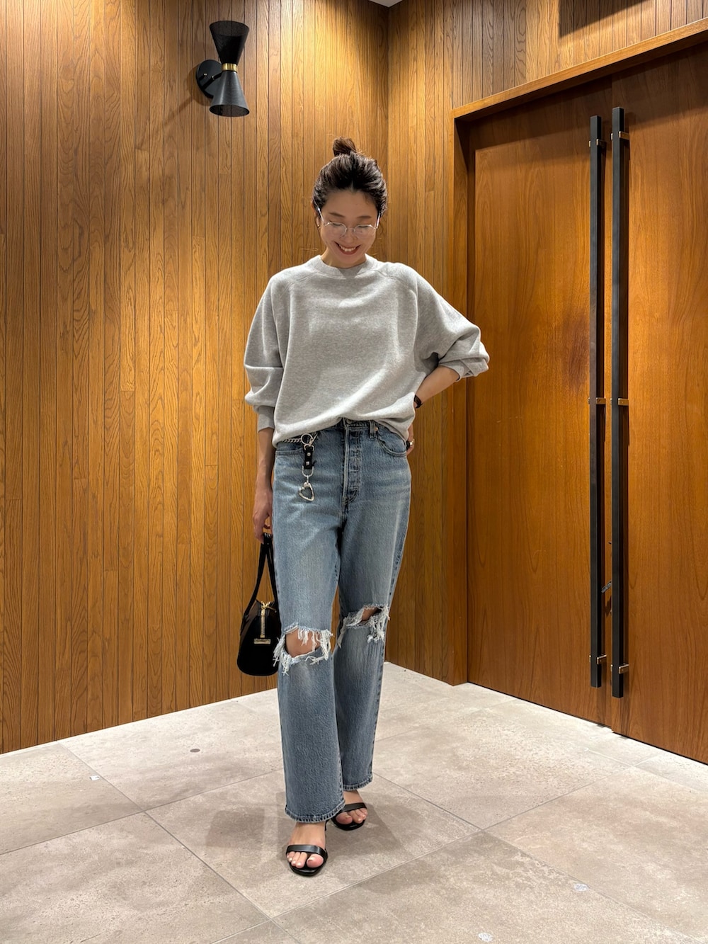 ブルー系のデニムパンツ、グレー系のニット/セーター、ブラック系のショルダーバッグを着用したレディースの秋コーディネートの4枚目の写真