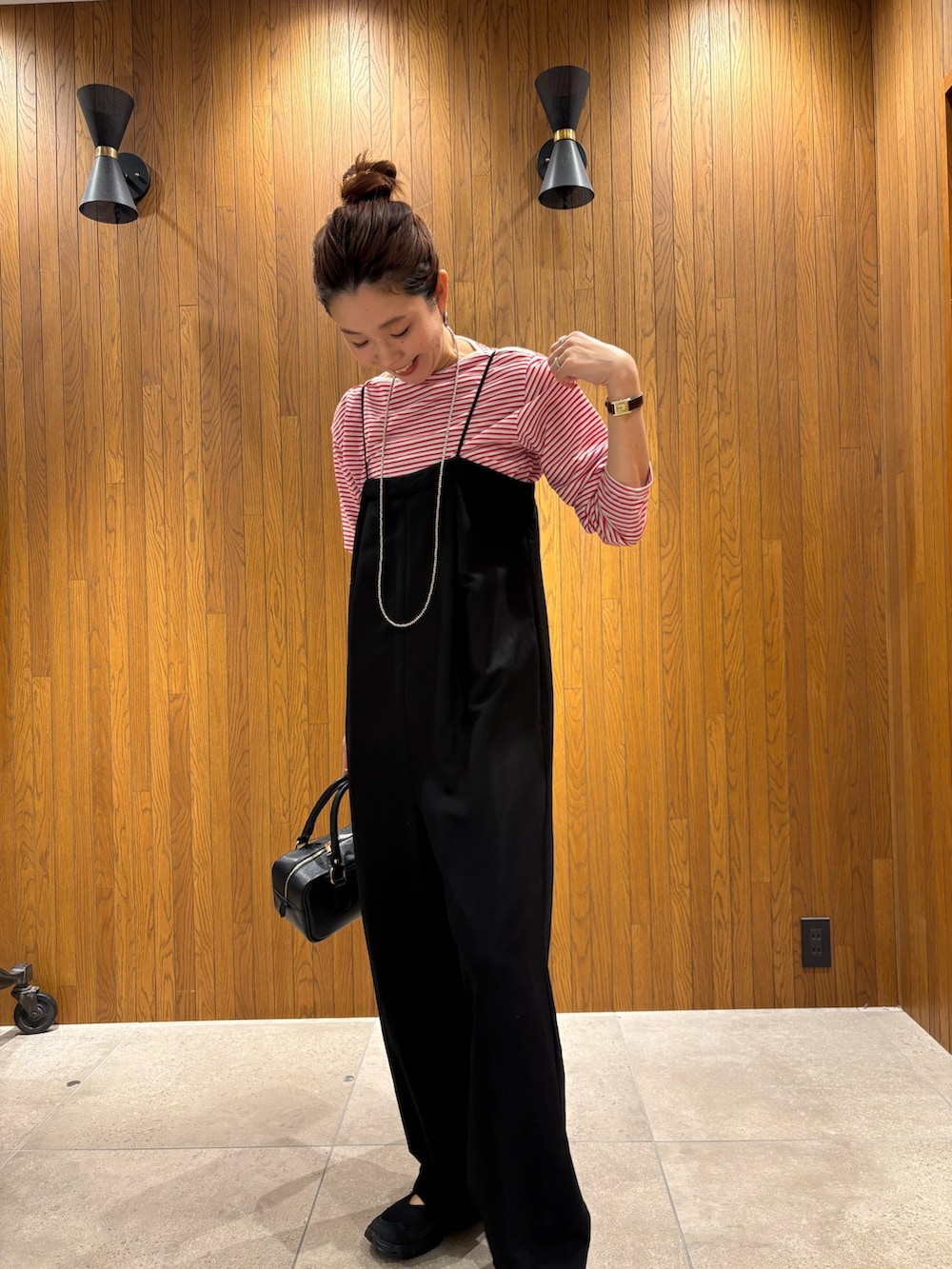 レッド系のTシャツ/カットソー、ブラック系のその他パンツ、ブラック系のハンドバッグを着用したレディースの春コーディネートの6枚目の写真