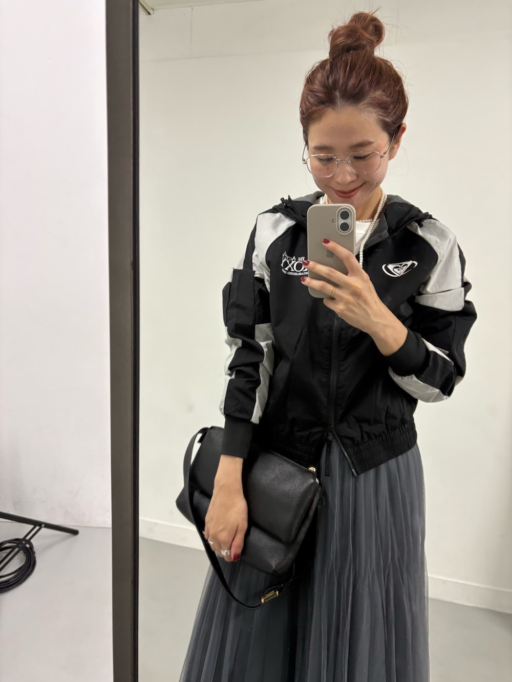 グレー系のスカート、ブラック系のナイロンジャケット、ブラック系のブーツを着用したレディースの夏コーディネートの7枚目の写真