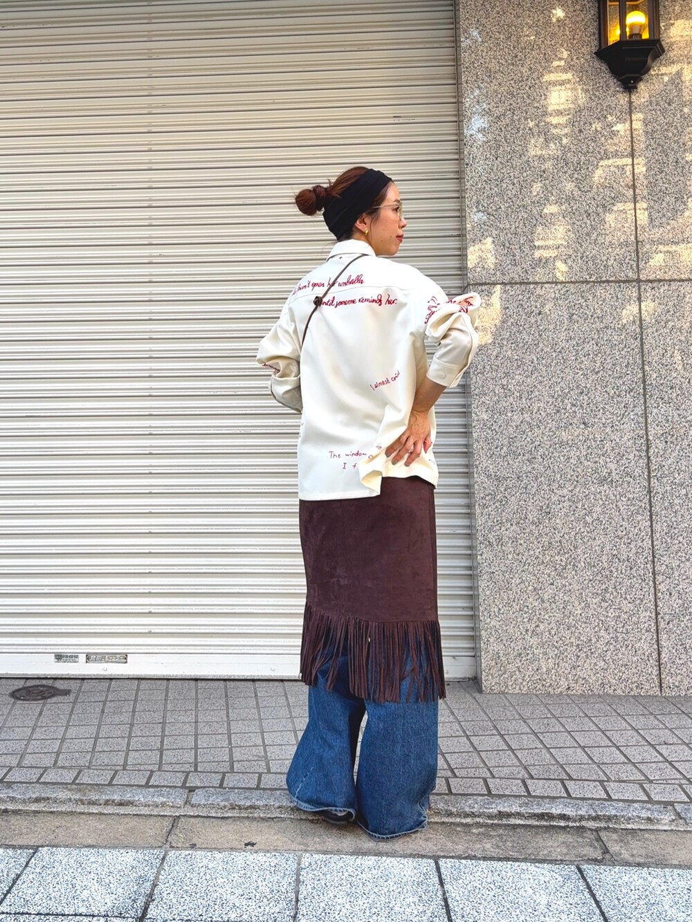 ホワイト系のTシャツ/カットソー、ブラウン系のスカート、ブルー系のデニムパンツを着用したレディースの秋コーディネートの3枚目の写真