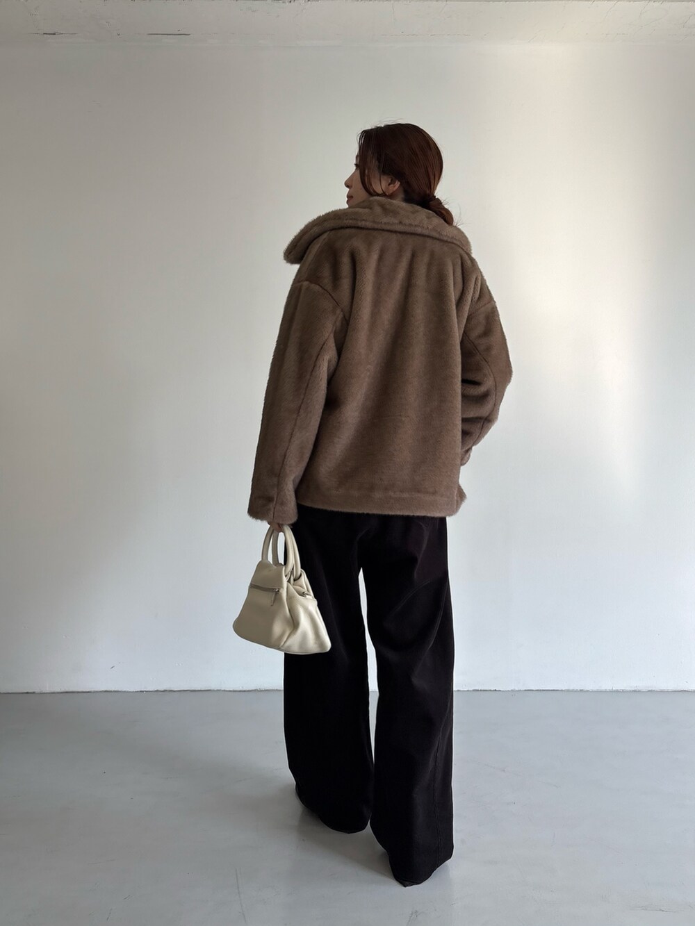 グレー系のその他パンツ、レッド系のニット/セーター、ブラック系のハンドバッグを着用したレディースの冬コーディネートの4枚目の写真