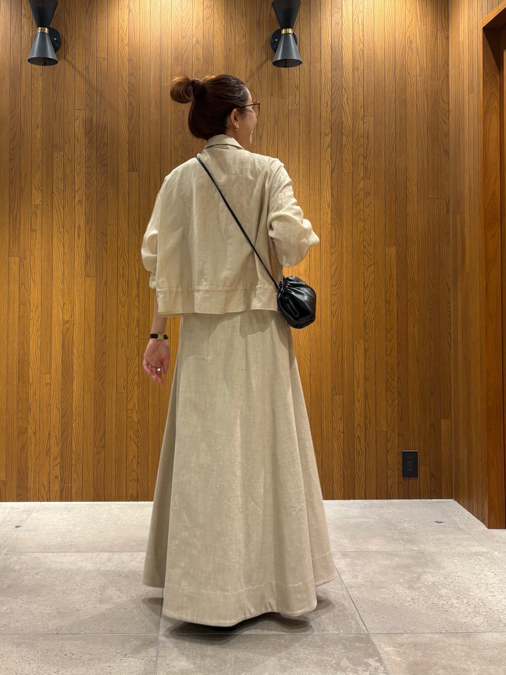 ベージュ系のスカート、ホワイト系のシャツ/ブラウス、ブラック系のショルダーバッグを着用したレディースの春コーディネートの3枚目の写真