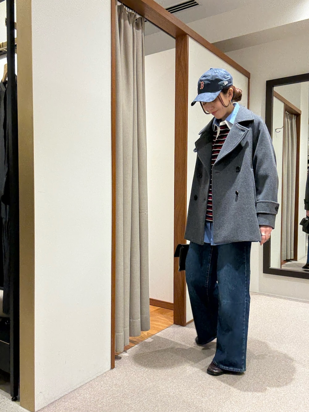 グレー系のピーコート、ブルー系のシャツ/ブラウス、レッド系のTシャツ/カットソーを着用したレディースの秋コーディネートの4枚目の写真