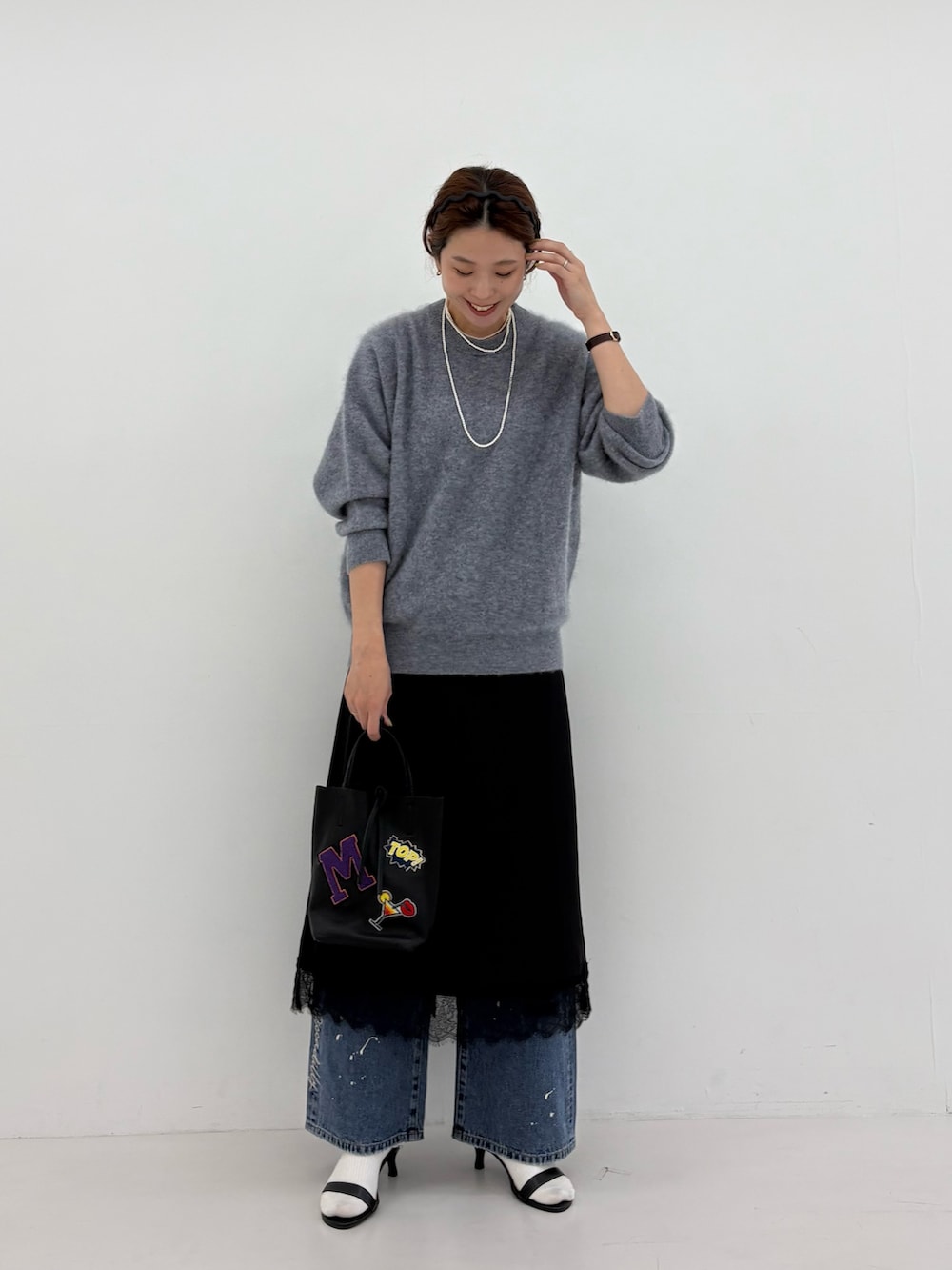 グレー系のニット/セーター、ブラック系のワンピース、ブルー系のデニムパンツを着用したレディースの秋コーディネートの6枚目の写真